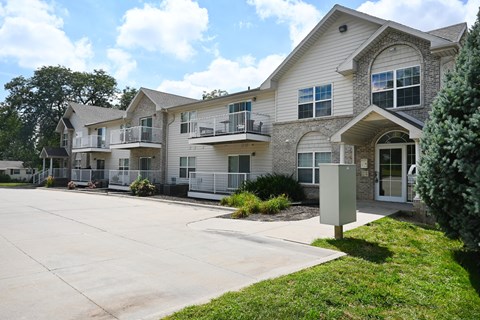 Apartment complex with a grey and white building and a sign on the grass.