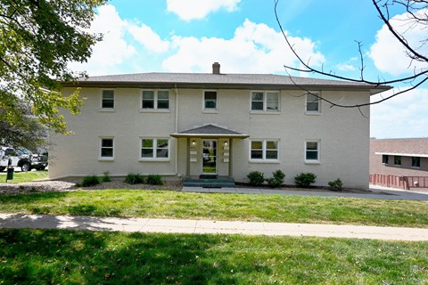 A white house with a green lawn in front.