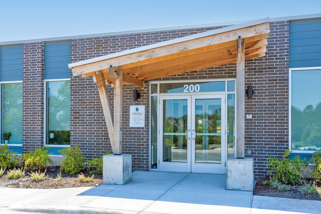 The front of a building with a wooden canopy and a sign that reads at Lofts at Fox Ridge, Raymore, MO