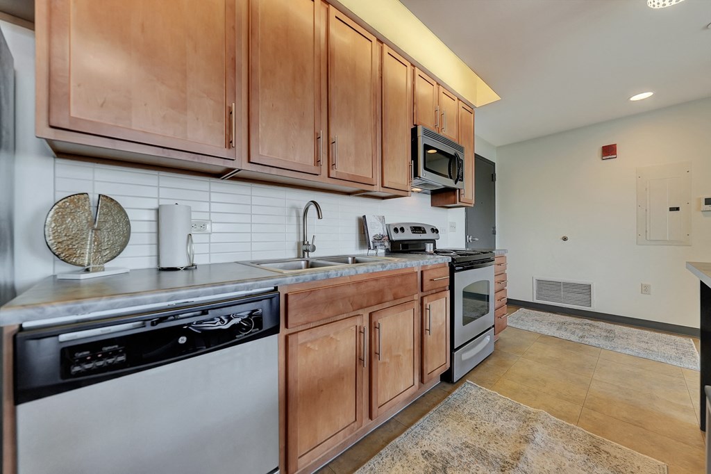 the kitchen is equipped with stainless steel appliances and wood cabinets at Parkhaus Apartments, Lincoln, NE
