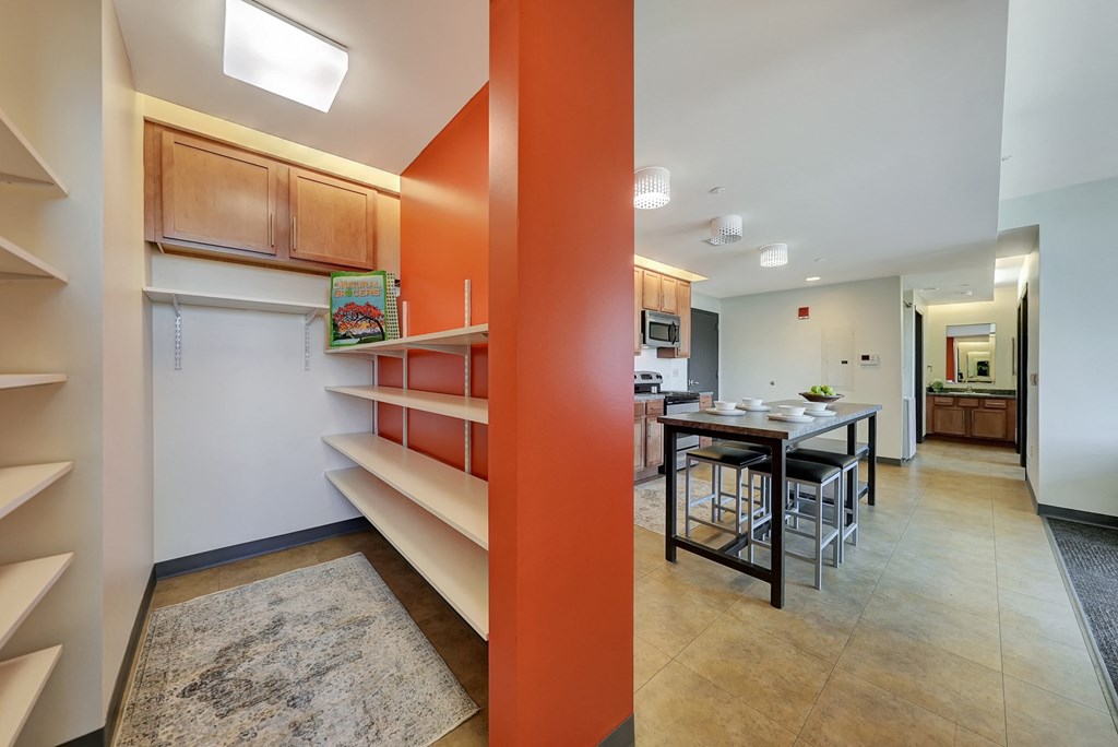 a dining room and kitchen with a table and chairs and a wall with shelves at Parkhaus Apartments,Nebraska 68508