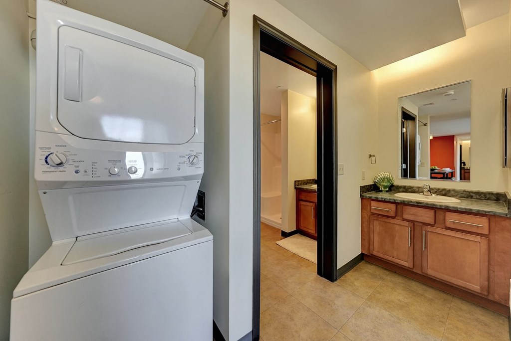 a washer and dryer in a bathroom with a sink and a mirror at Parkhaus Apartments, Lincoln, 68508