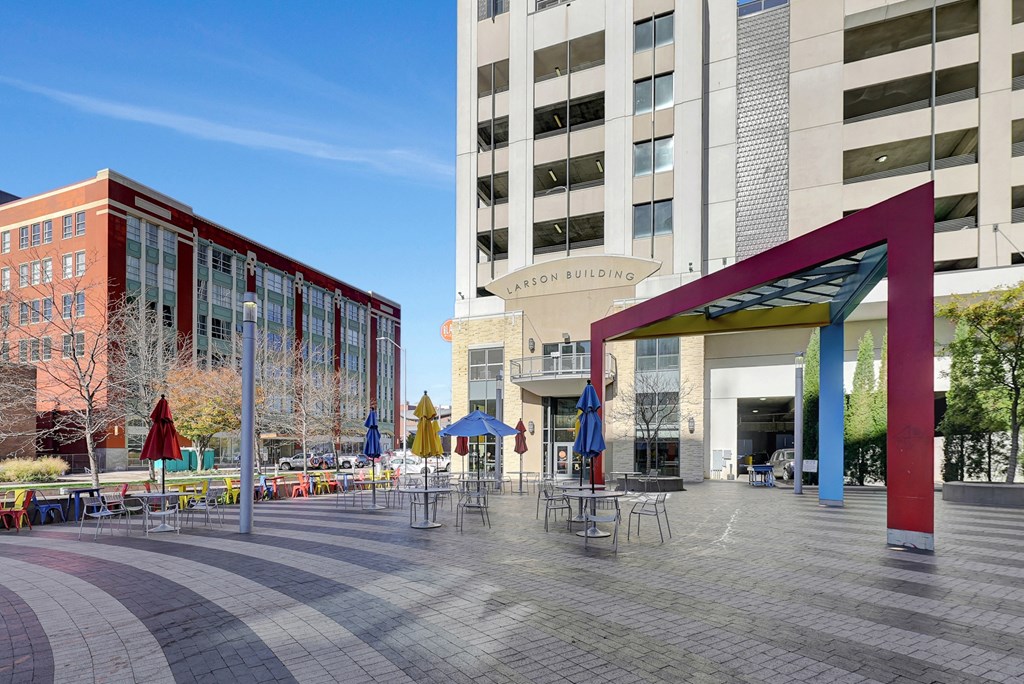 a plaza with tables and umbrellas in front of a building at Parkhaus Apartments,Nebraska