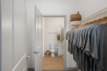 A bathroom with a toilet, a plant, and a rack of towels.at Converge KC Uptown, Kansas City, 64111