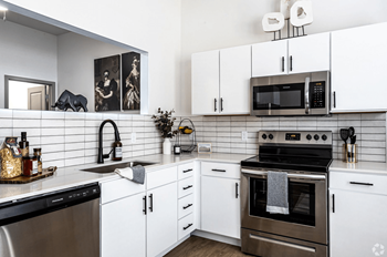 A modern kitchen with white cabinets and a black stove top.at Converge KC Uptown, Missouri