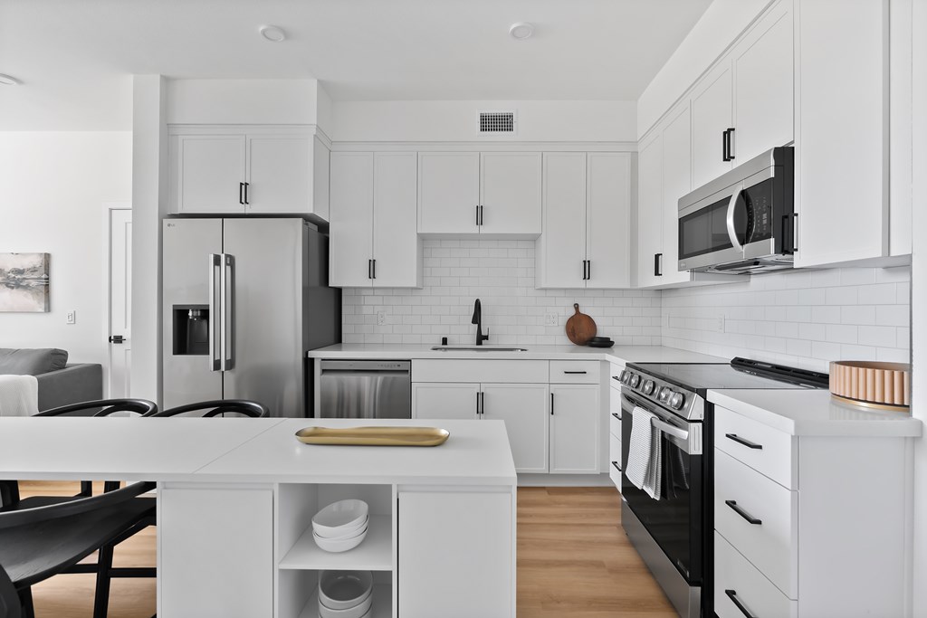 A modern kitchen with white cabinets and appliances.