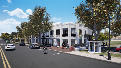A street view with cars, trees, and a white building with a blue awning.