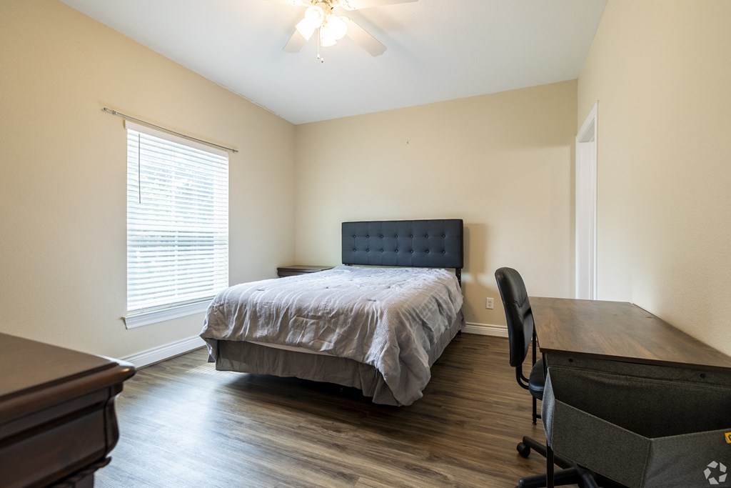 a bedroom with a bed and a desk and a window