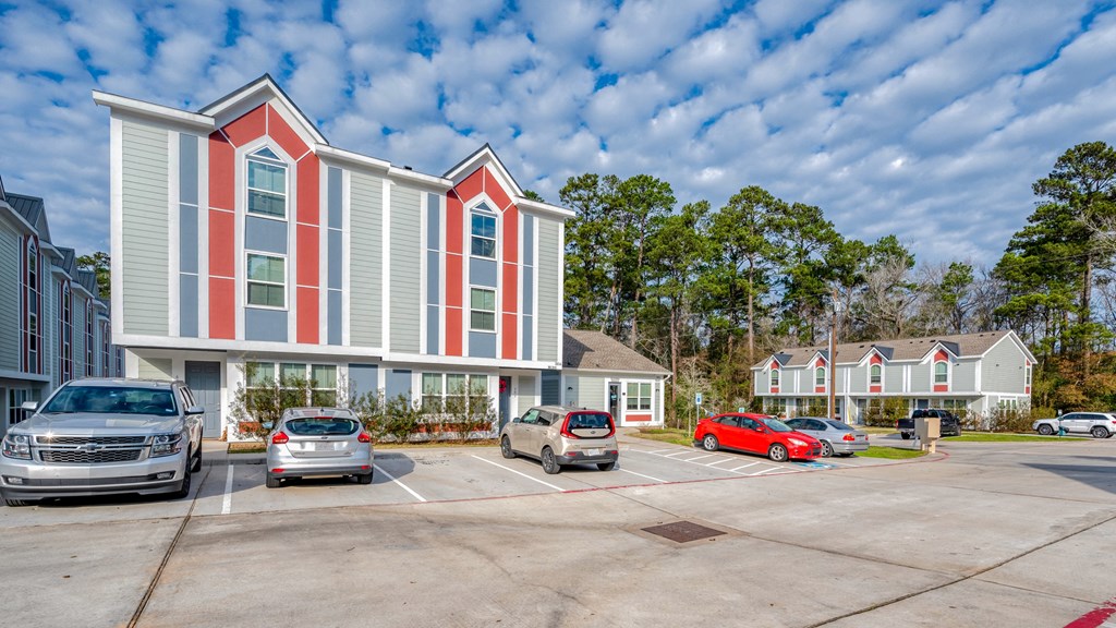 an empty parking lot with cars in front of a building with red and white facade