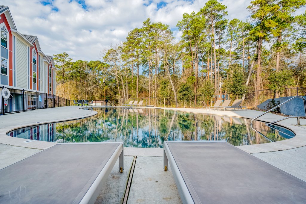 a pool with benches next to a building and trees