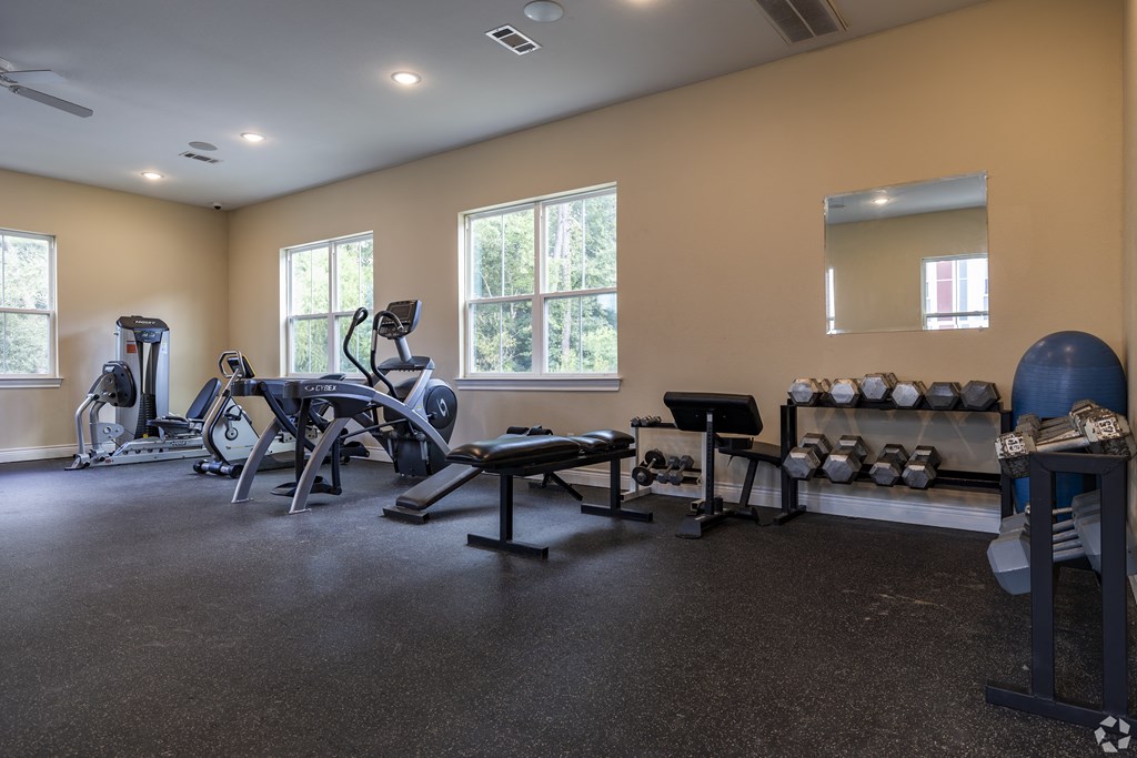 a gym with weights and cardio equipment in a facility with windows