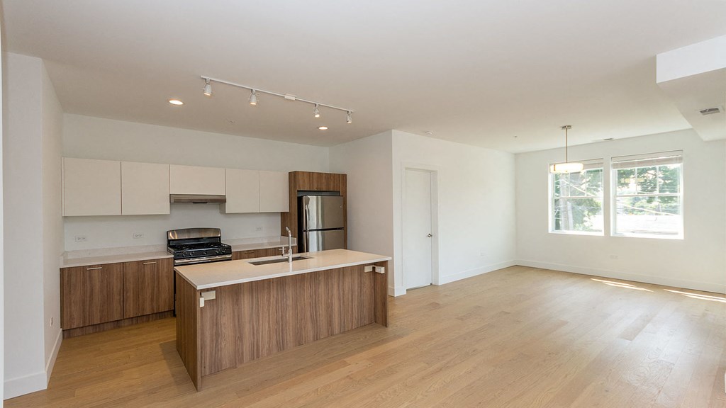 a kitchen with wooden cabinets and a counter top in an empty living room