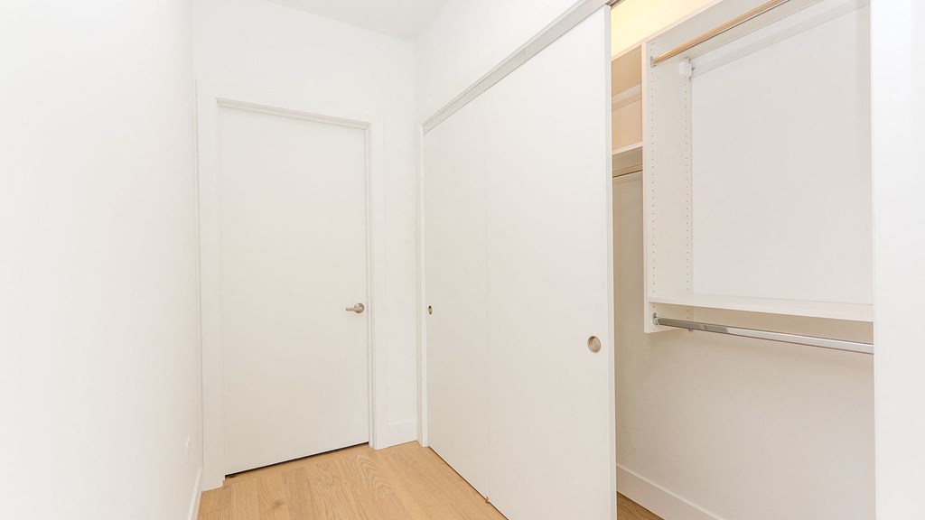 a bedroom with white walls and a closet and a door
