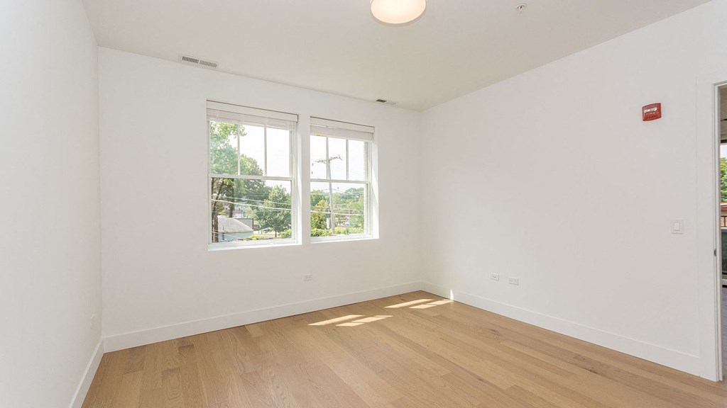 a living room with white walls and a window and wooden floors