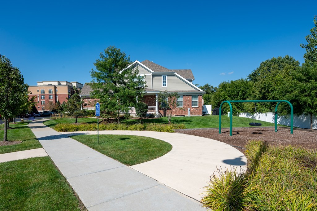 A playground with a slide and a house in the background.