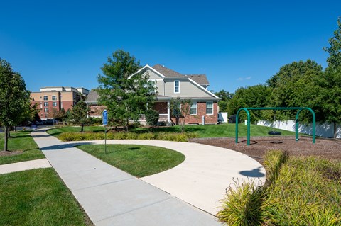 A playground with a slide and a house in the background.