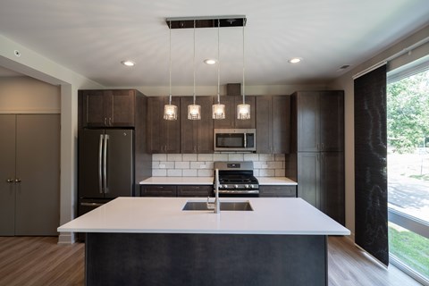 A modern kitchen with a large island and dark brown cabinets.