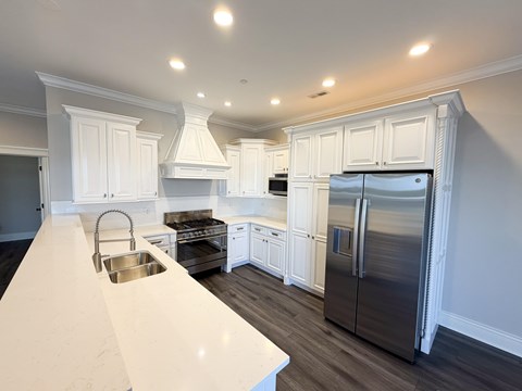 A kitchen with white cabinets and a stainless steel refrigerator.