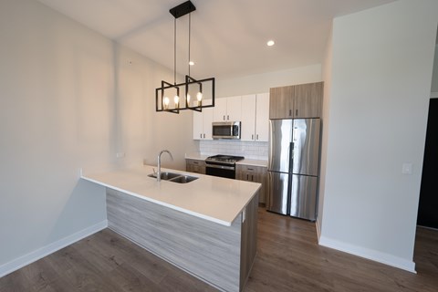 A modern kitchen with a white countertop and stainless steel appliances.