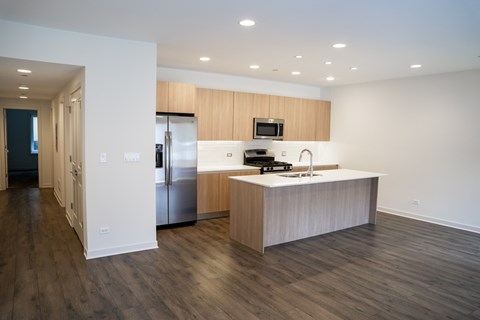 A modern kitchen with a refrigerator, microwave, and oven.