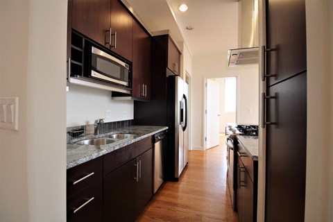 A kitchen with black appliances and brown cabinets.