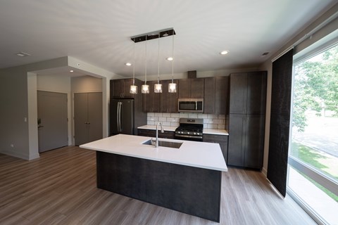 A modern kitchen with a large island and dark wood cabinets.