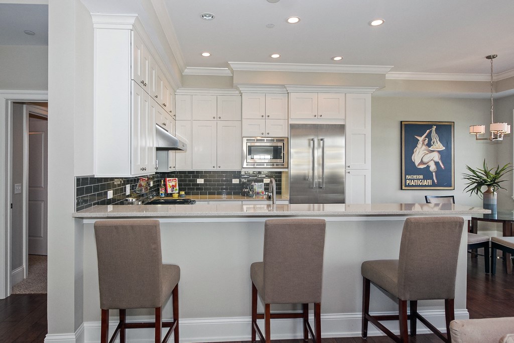 a kitchen with white cabinets and a bar with chairs  at Countryside 10765, Illinois, 60525