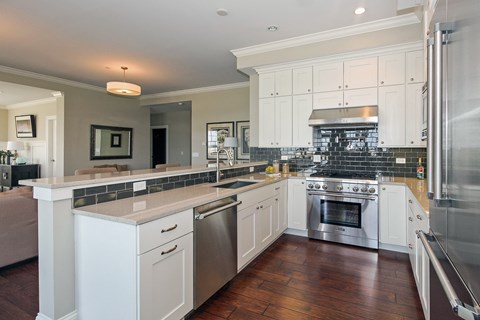 a large kitchen with white cabinets and stainless steel appliances