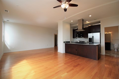 A spacious kitchen with wooden floors and a ceiling fan.