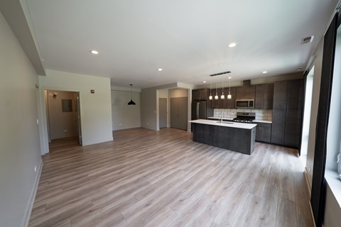 A spacious kitchen and living room with wooden flooring and modern appliances.