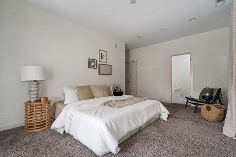 A bedroom with a white bed and a grey carpet.
