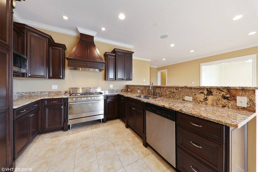 a large kitchen with granite counter tops and dark cabinets