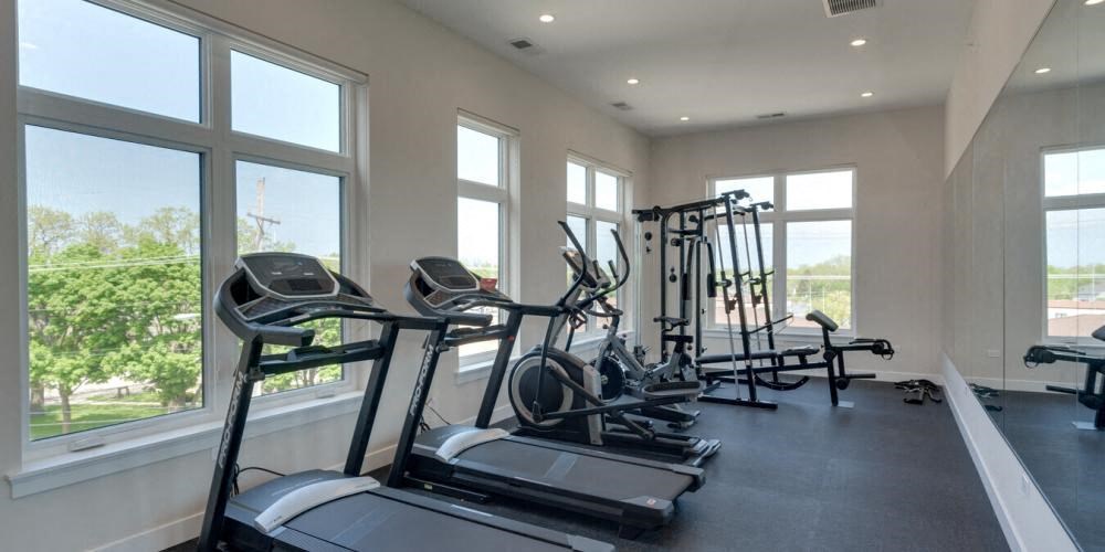 a row of exercise equipment in a gym with large windows  at Highwood 246, Highwood, Illinois