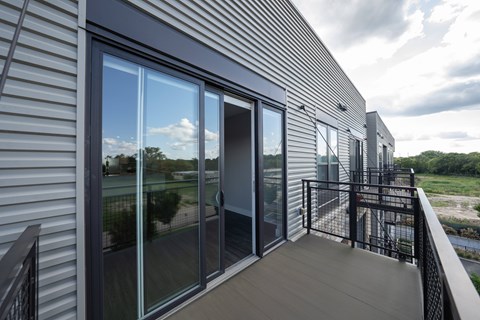 A balcony with a glass door and a view of the outdoors.