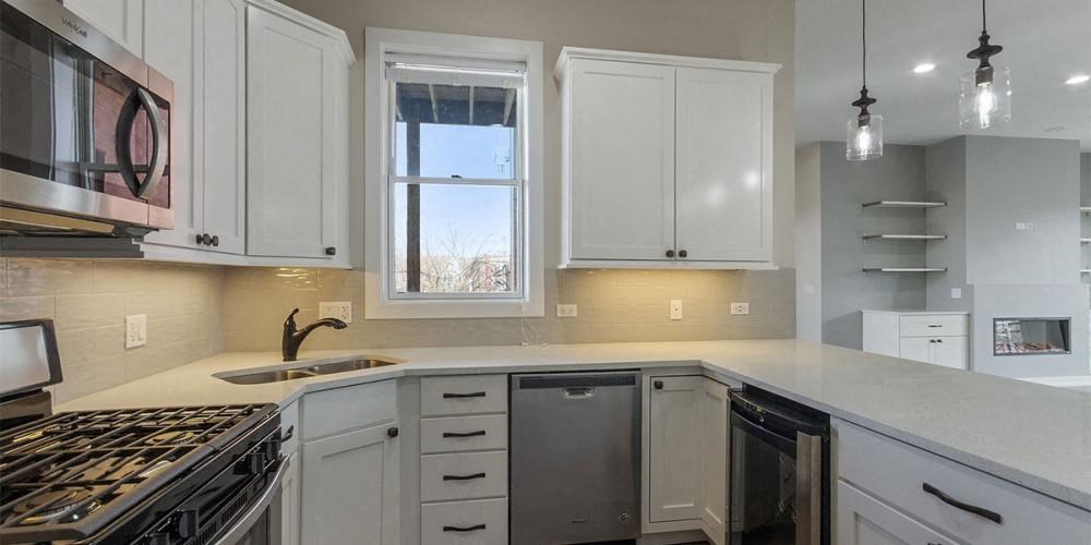 a kitchen with white cabinets and a stove and a sink  at Elston 3434, Chicago, Illinois