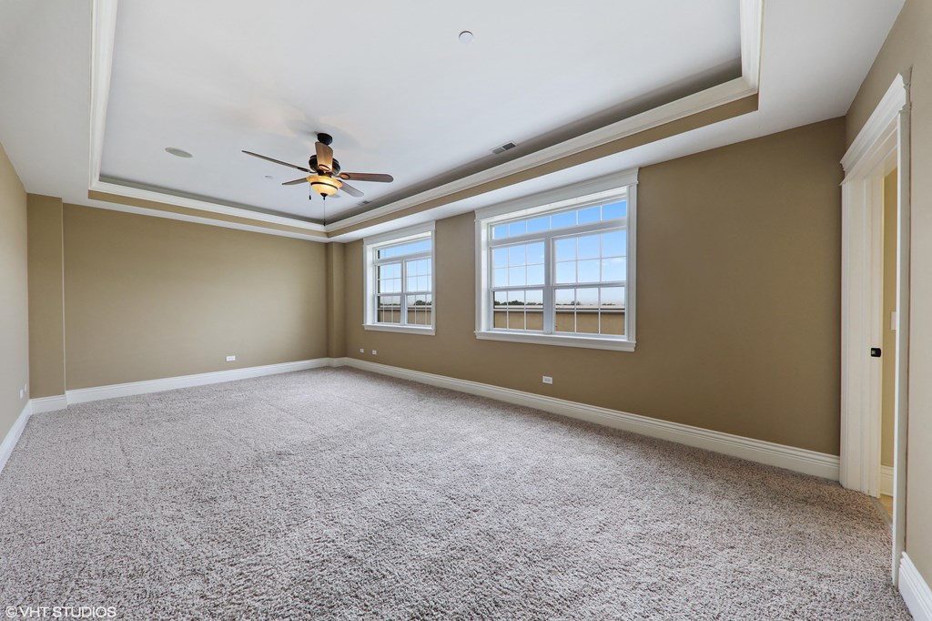 an empty living room with a ceiling fan and two windows