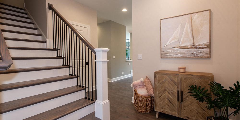 a living room with a staircase and a painting on the wall at Countryside Townhomes, Illinois, 60525