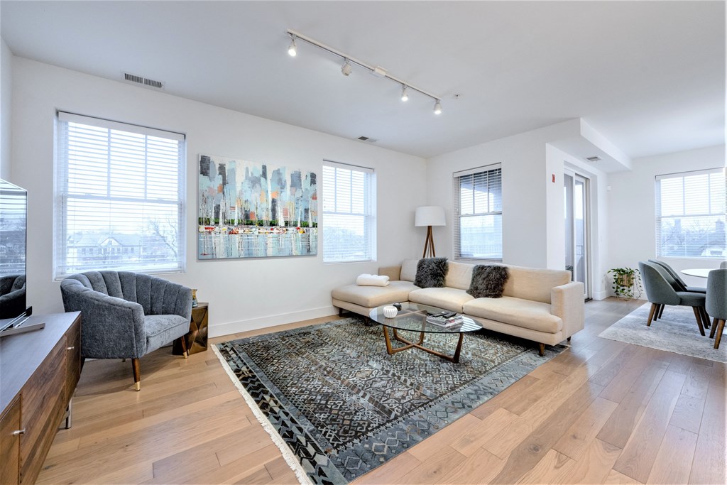 a living room with a couch and two chairs and a rug