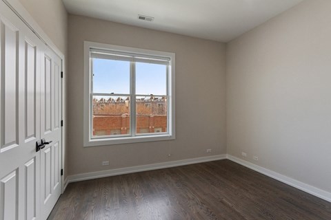 an empty living room with a window and wooden floors