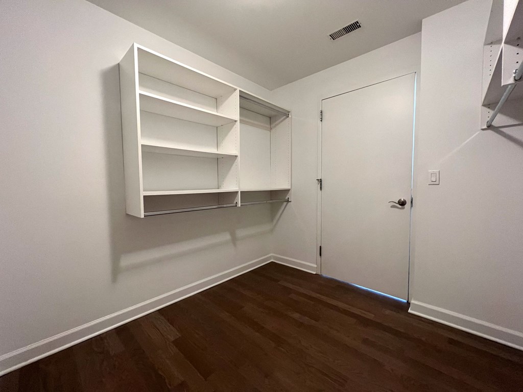 a bedroom with white walls and a closet with shelves