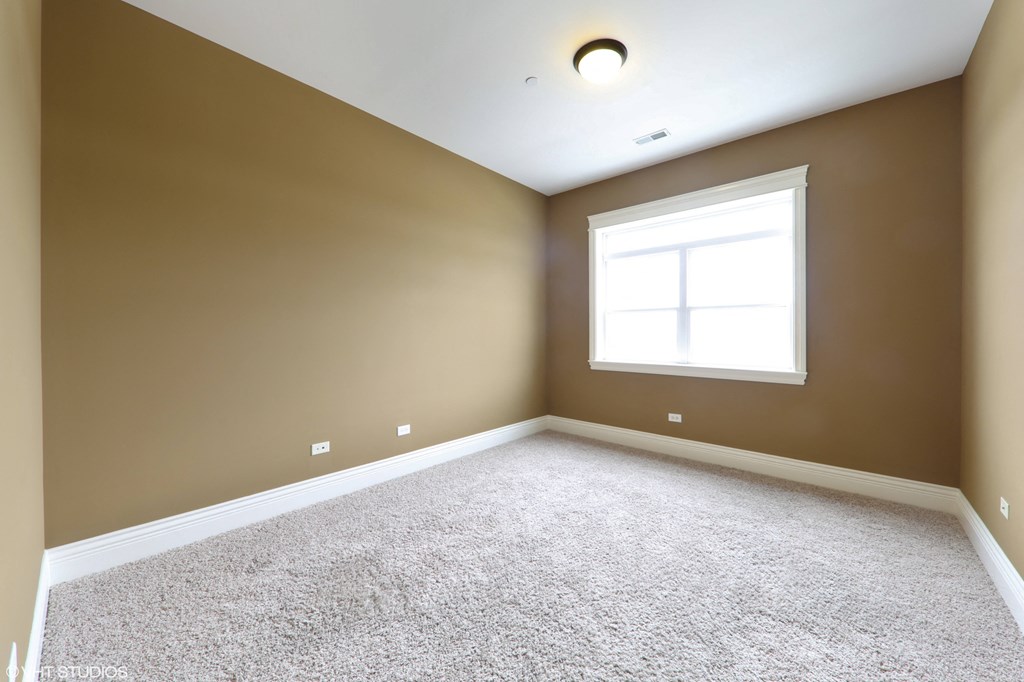 an empty room with a window and carpet