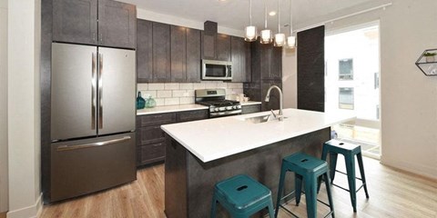 a kitchen with a white counter top and a stainless steel refrigerator
