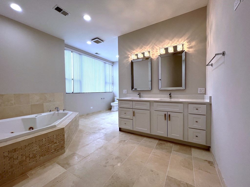 a large bathroom with a tub and two sinks and two mirrors