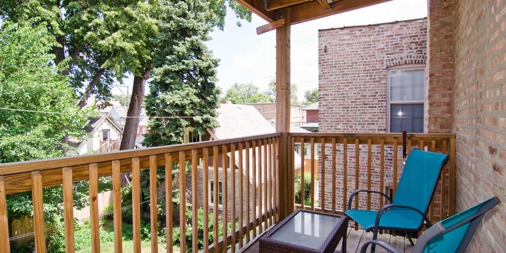 a porch with two chairs and a brick building at Tripp 4321, Chicago