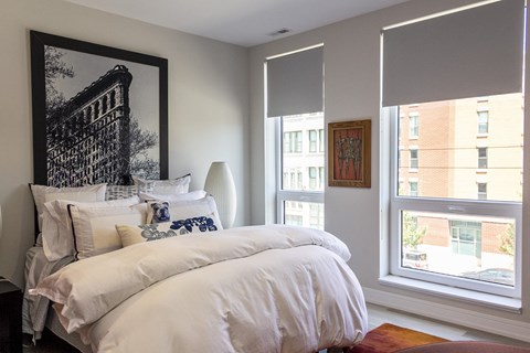 a bedroom with a bed and two windows and a painting on the wall