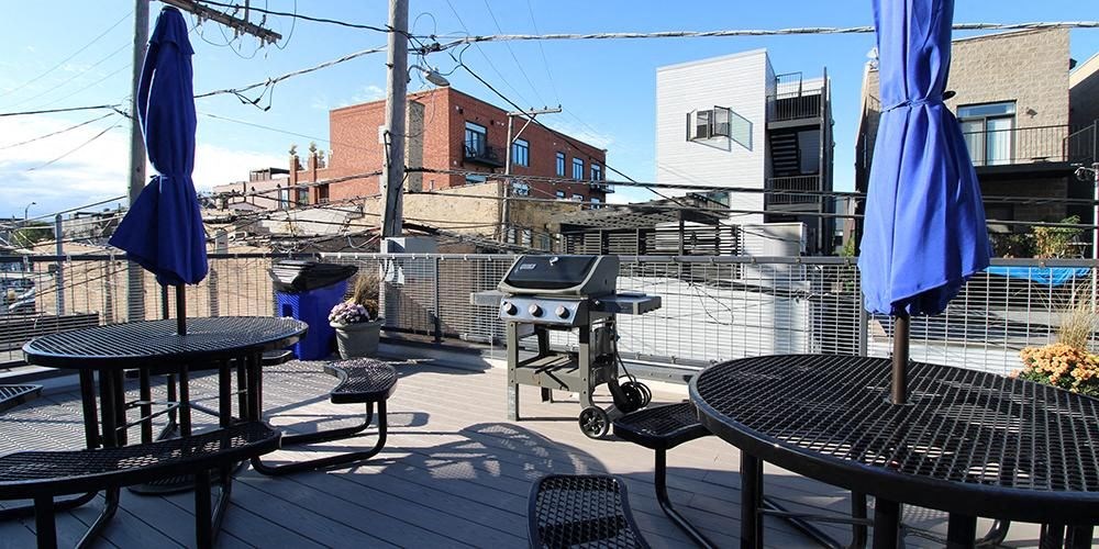a patio with tables and chairs and a barbecue grill  at Fullerton 1540, Chicago, Illinois