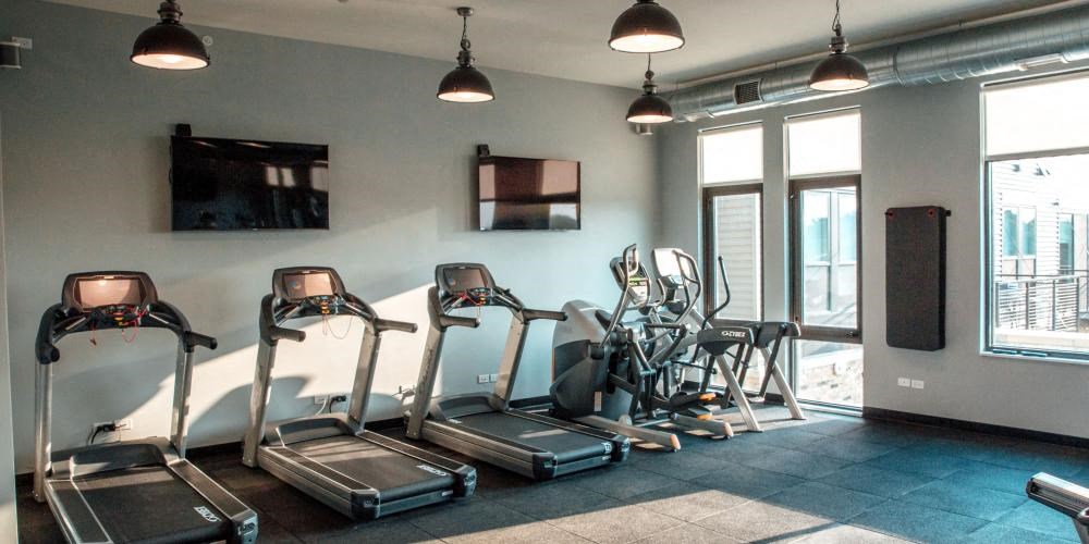 a gym with cardio equipment and a tv on the wall at Barrington 101, Illinois, 60010