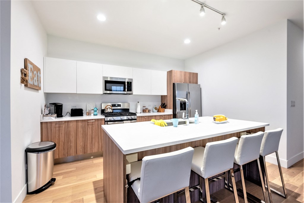 a kitchen with a large island and white chairs