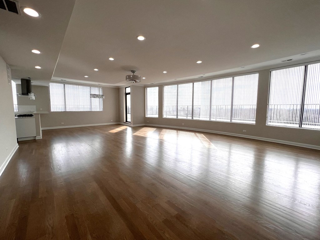 an empty living room with wood floors and large windows