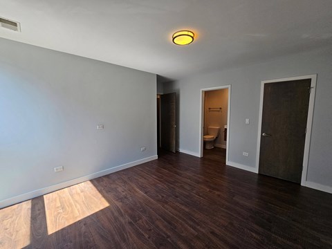 a living room with wood floors and a door to a bathroom